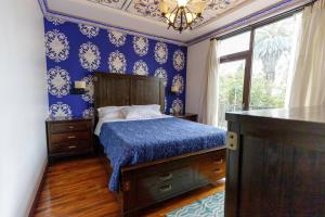 a bedroom with blue walls and a bed and a window at Hotel Azul de la Plaza in Cuenca