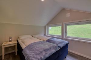 un letto in una piccola stanza con due finestre di Flotunet - Jørnhuset a Stryn
