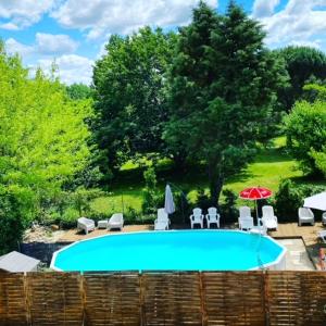 a swimming pool with chairs and umbrellas at Auberge de Lamagistere in Lamagistère