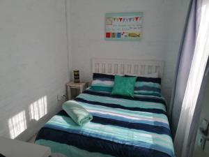 a small bedroom with a bed with green and blue pillows at Die Waenhuis in Arniston
