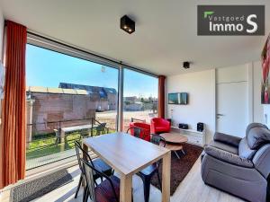 a living room with a table and chairs and a large window at New Dahlia in Bredene