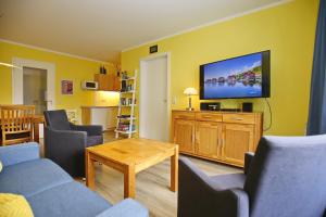 sala de estar con TV de pantalla plana en una pared amarilla en Dünenblick Wohnung 42, en Boltenhagen