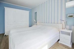 Dormitorio blanco con cama blanca y paredes azules en Dünenblick Wohnung 42, en Boltenhagen