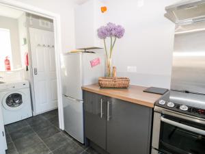 a kitchen with a refrigerator and a vase of purple flowers at Seagull Cottage in Bude