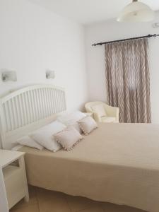 a bedroom with a white bed and a chair at Anixi Hotel in Ornos