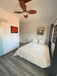 a bedroom with a white bed and a ceiling fan at Casa do Beco B&B Douro - Guest House in Parambos