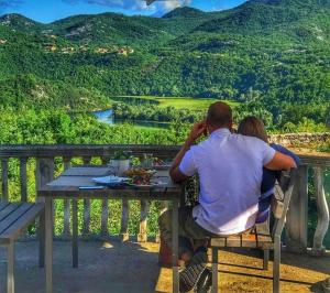 a man and a woman sitting at a table looking at a mountain at Skadar Lake Family Resort in Rijeka Crnojevića