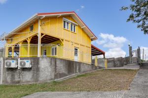 ein gelbes Haus mit einem Balkon an der Wand in der Unterkunft Le Palma Christi in Le Carbet