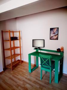 - Escritorio verde con monitor y silla en la habitación en Cornu Karma Apartment Siuranella, en Cornudella