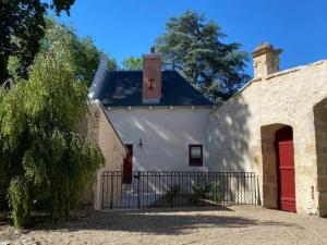 a white building with a red door and a gate at Gîte élégant avec jardin privé, climatisation et parking à Ainay-le-Vieil - FR-1-586-7 in Ainay-le-Vieil