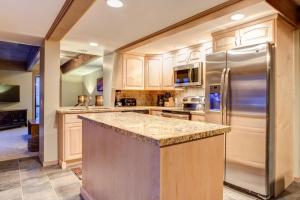 uma cozinha com armários de madeira e um frigorífico de aço inoxidável em Empire Duplex em Park City