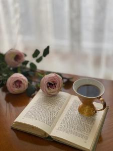 an open book with a cup of coffee and roses at Stan na dan Oplenac in Topola