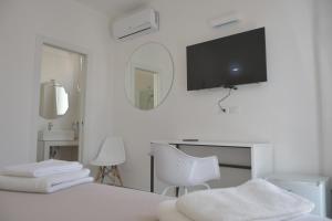 a bedroom with a bed with a desk and a tv on the wall at Estatesalento in Leuca
