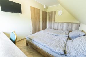 a bedroom with a bed and a flat screen tv at Pokoje Gościnne Butryny in Butryny