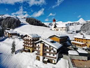 a building on a snow covered mountain with a church at Hotel Garni Enzian in Damuls