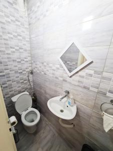 ein Badezimmer mit einem WC, einem Waschbecken und einem Spiegel in der Unterkunft CALLA - Modern & Cozy Main Square Apartment in the City Shopping Center - PARKING SLOT with parking security in Skopje