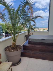 a balcony with a bed and two palm trees at Hotel Ambassador in Rimini