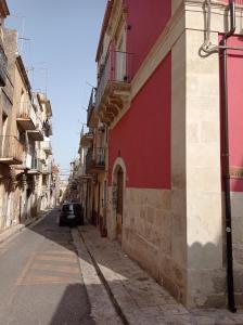 een rood gebouw met een auto op straat bij Locazione turistica da Enzo e Maria in Ragusa