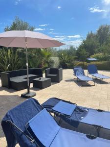 eine Terrasse mit zwei blauen Stühlen und einem Sonnenschirm in der Unterkunft Villa 180 m2 piscine in Draguignan