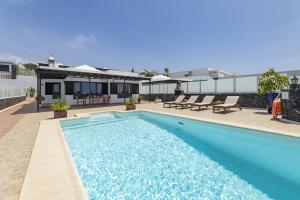 a large blue swimming pool in front of a house at Villa 21 in Puerto del Carmen