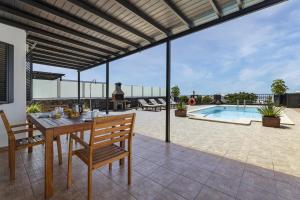 a patio with a table and chairs and a pool at Villa 21 in Puerto del Carmen