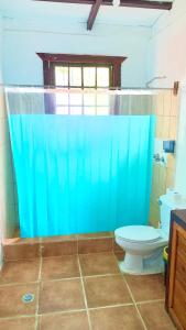 a bathroom with a toilet and a blue shower curtain at Casa Nara in Puerto Viejo