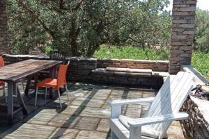 a patio with a table and chairs and a stone wall at Cottage amidst vines and Oak Trees in Ioulis