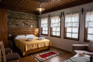 a bedroom with a bed and two chairs and windows at Hotel Borklad in Berat