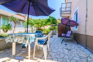 - une table, des chaises et un parasol sur la terrasse dans l'établissement Apartmani Loreta, à Mali Lošinj