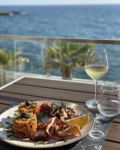 a plate of food on a table with a glass of wine at Apartments & Rooms Elite in Dobra Voda
