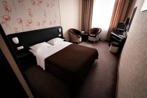 クラスノダールにあるФорум Отель Краснодарのベッド1台と椅子2脚が備わるホテルルームです。