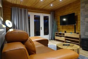 ein Wohnzimmer mit einem Sofa und einem Flachbild-TV in der Unterkunft Le Chalet de Hermeton in Hastière-par-delà