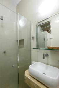 ein Bad mit einem Waschbecken und einer Glasdusche in der Unterkunft Sossego em Copacabana - Vista arborizada - BR1009 Z4 in Rio de Janeiro