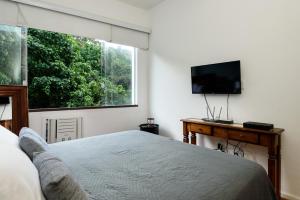 Schlafzimmer mit einem Bett und einem Flachbild-TV in der Unterkunft Sossego em Copacabana - Vista arborizada - BR1009 Z4 in Rio de Janeiro