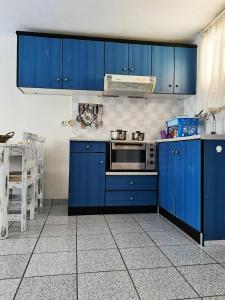 a kitchen with blue cabinets and a stove at Sea waves apartments in Nea Epidavros