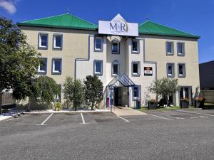 a large white building with a mr sign on it at Hôtel M&R in Ifs