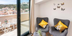 Habitación con 2 sillas y balcón con mariposas en la pared. en Apartments Ante, en Hvar