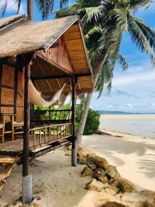 
a sandy beach with a wooden bench and palm trees at Castaway Beach Bungalows in Hinkong
