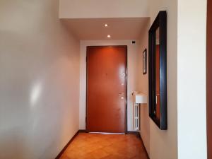 pasillo con puerta marrón y espejo en TOGLIATTI 1 BUSINESS APARTMENT by ITALYVING, en Rho