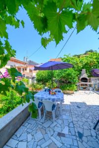 - une table avec un parasol et des chaises sur la terrasse dans l'établissement Apartmani Loreta, à Mali Lošinj