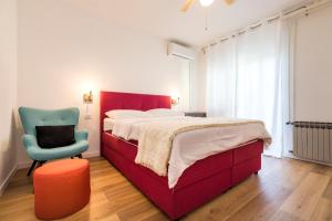 um quarto com uma cama vermelha e uma cadeira azul em Alaburic rooms & apartment em Mali Lošinj