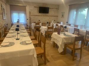 a dining room with white tables and chairs and a tv at Tenuta Micoli in Frisa