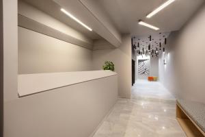 a hallway with a white wall with a chandelier at Thisean Modern Suites By Athens Stay in Athens +18 photos