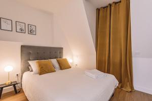 a bedroom with a large white bed with yellow pillows at REIMS - Place du Forum - Cathédrale - Terrasse in Reims