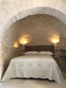 1 dormitorio con 1 cama en una pared de piedra en Tipico Resort, en Alberobello