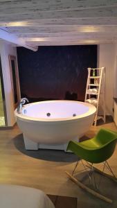 a bath tub in a room with a green chair at La estrella del viajero in Casas del Abad