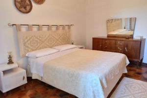 a bedroom with a bed and a dresser and a mirror at La Terrazza sul Melograno - Magomadas in Magomadas