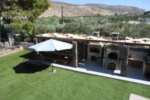 an outdoor grill with a roof on a lawn at Orion Eco Suites in Karteros