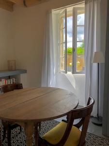- une table et des chaises en bois dans le salon doté d'une fenêtre dans l'établissement Chambre d'hôtes La grange, à Chalagnac