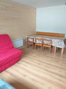 - un salon avec une table et un canapé rouge dans l'établissement Appartement au pied du PIC du Midi à La MONGIE, à La Mongie